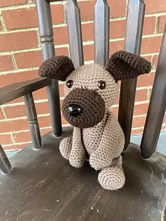 Crocheted dog sitting on chair.