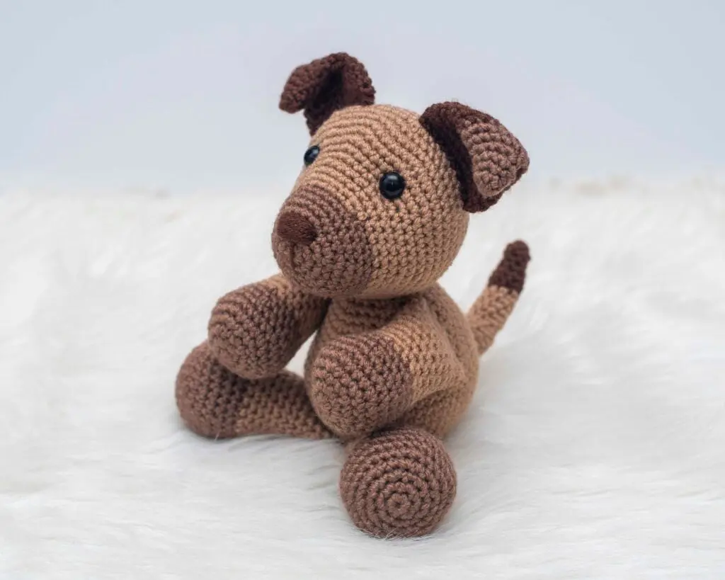 Crocheted brown dog toy sitting