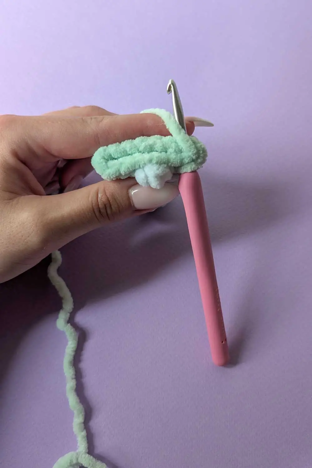 Hand holding crochet hook and yarn