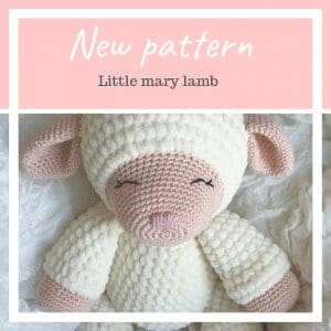 A crochet lamb stuffed animal with a white fluffy body and pink face, ears, and limbs is shown on a white fabric background. Text above reads New pattern and Little mary lamb. Perfect for those learning how to crochet a lamb plushie.