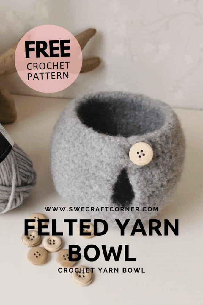 A gray felted crochet yarn bowl with a wooden button sits on a white surface, surrounded by loose wooden buttons and a skein of gray yarn. Text on the image promotes a free crochet pattern for this stylish crochet organizer.