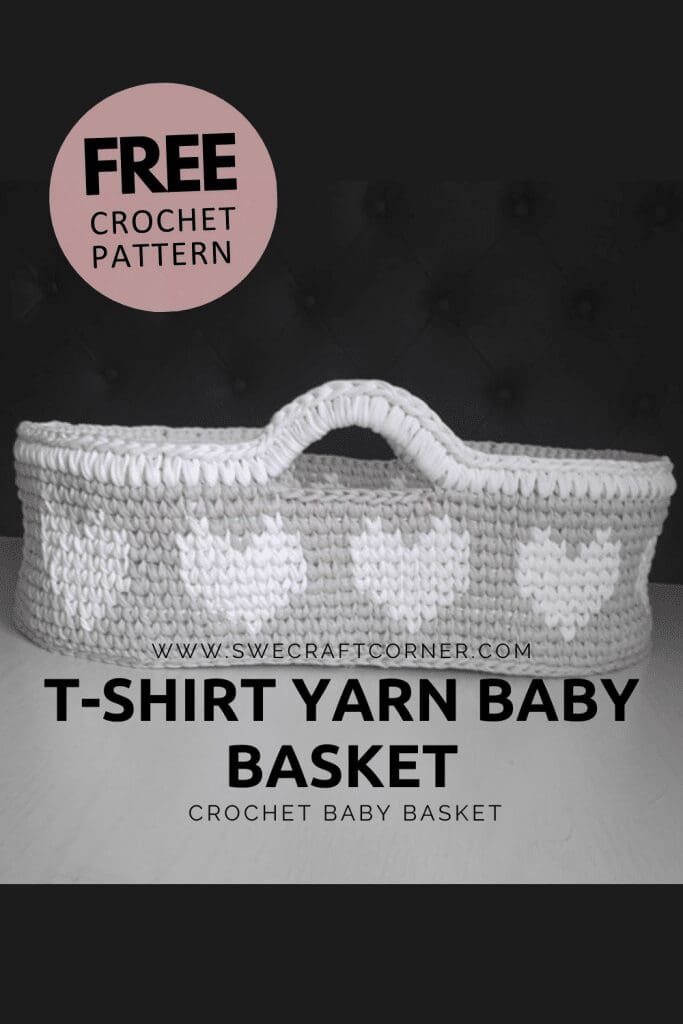 A crochet baby basket made from white and gray yarn with a handle and heart patterns, displayed on a dark background. Text reads FREE crochet pattern and T-shirt yarn baby basket.