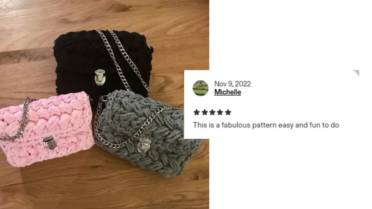 Three chunky knit Clutch purses—black, pink, and gray—crafted with T-shirt yarn and adorned with silver chains sit on a wooden floor. A review rates the crochet pattern five stars, calling it fabulous, easy, and fun to do.