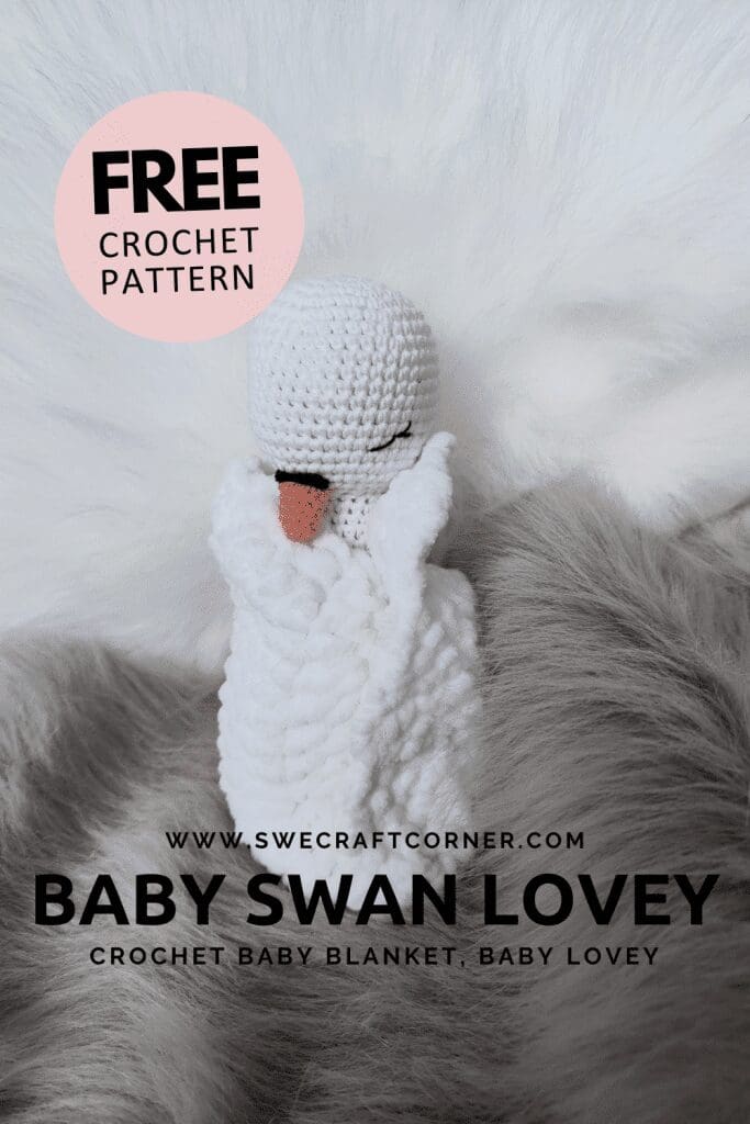 A crocheted white swan lovey with an orange beak rests on a soft, furry, white and gray blanket. The image advertises a free crochet chenille lovey pattern for a crochet baby comfort blanket at swecraftcorner.com.