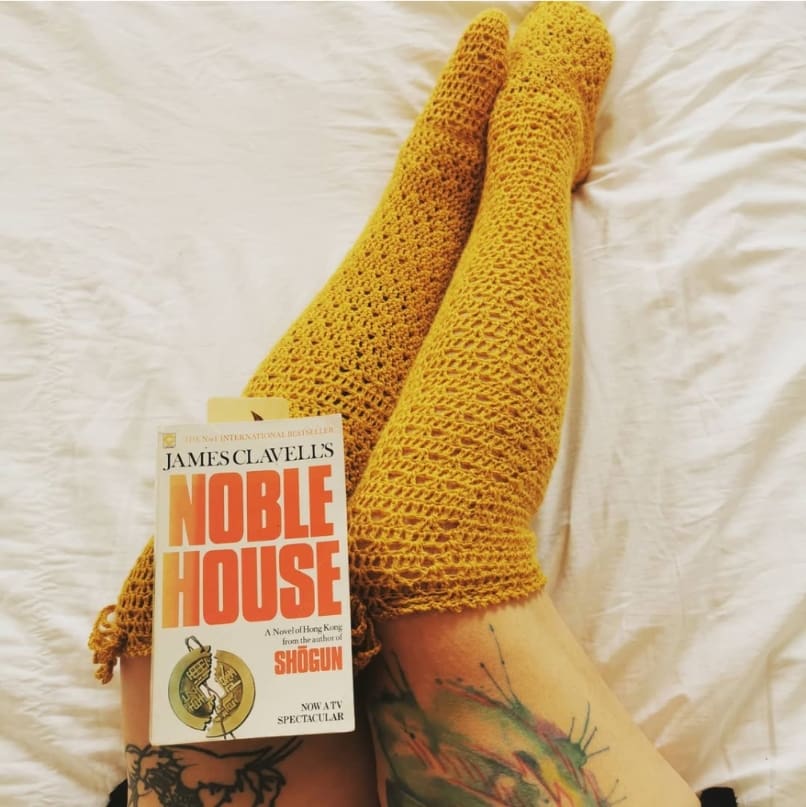 Cozy feet with thigh high socks made from this free crochet pattern with a book on bed