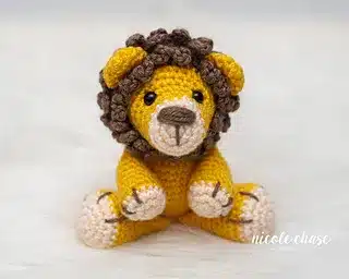 Crocheted lion plush toy sitting