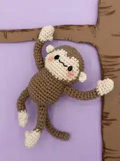Crocheted monkey hanging on tree