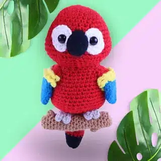 Crocheted red parrot on branch