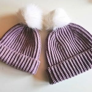 Two purple Crochet ribbed beanies with white pom poms made from this pattern