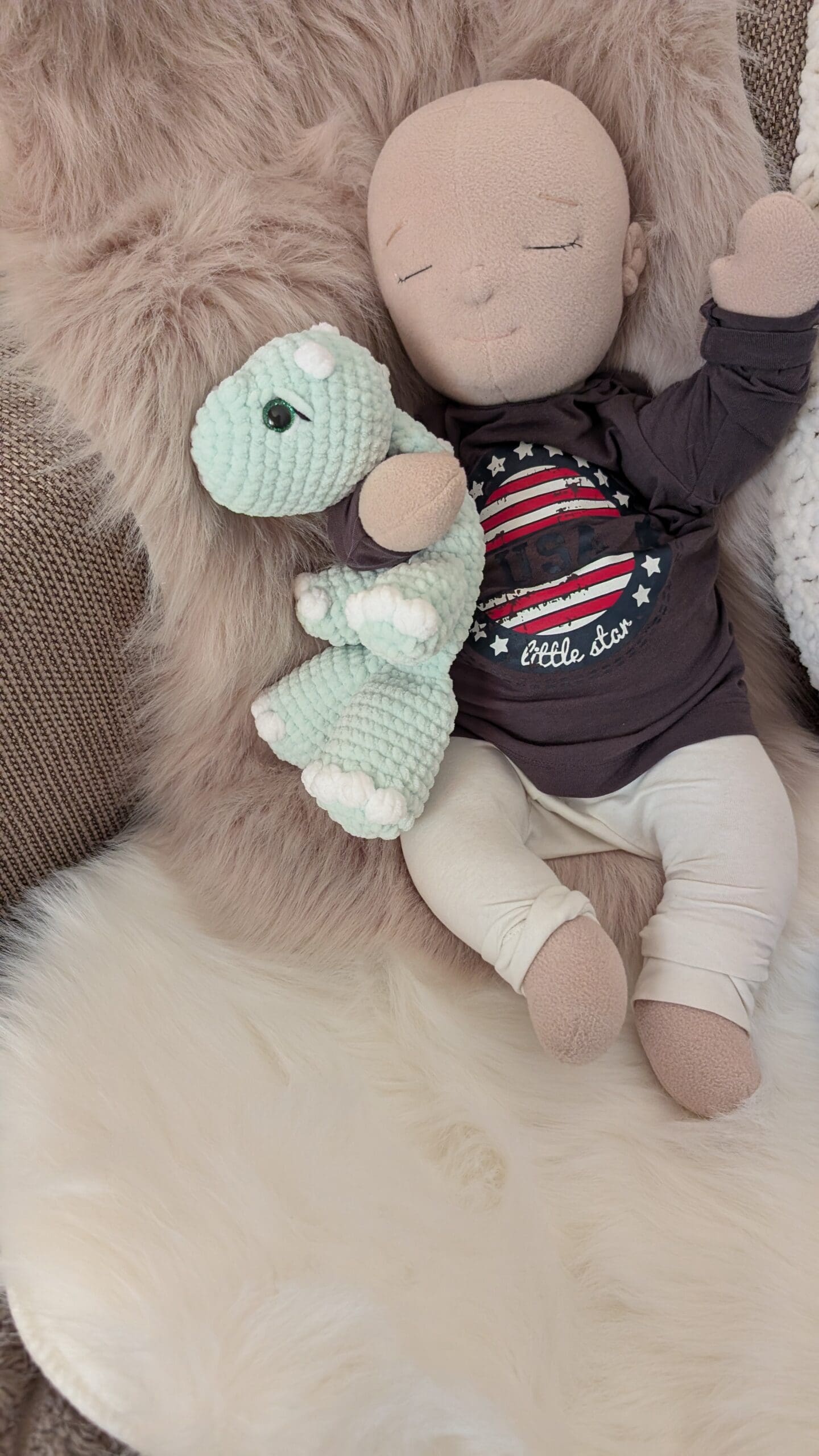 Doll with crocheted dinosaur lovey on fur