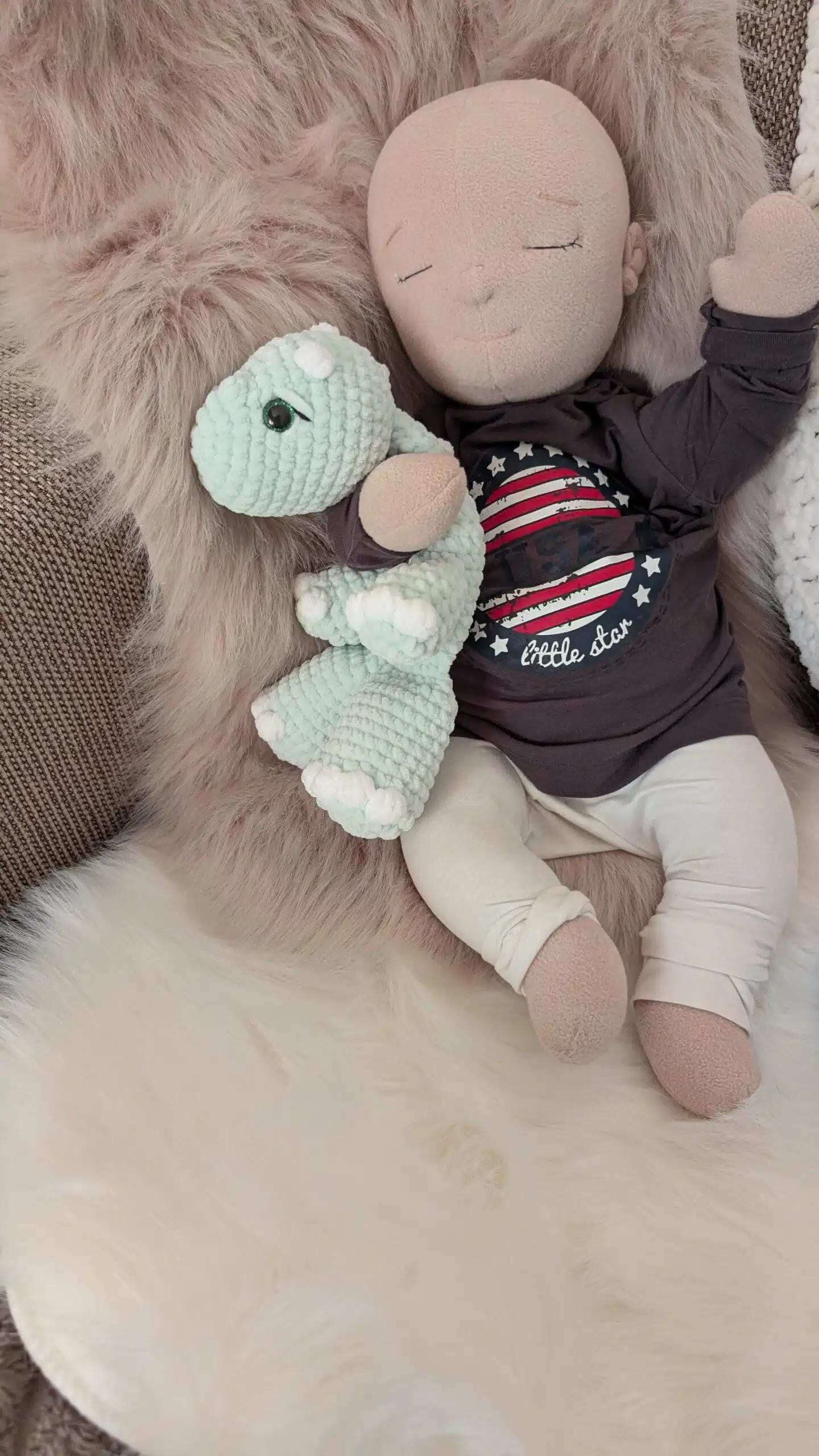 Doll with crocheted dinosaur lovey on fur
