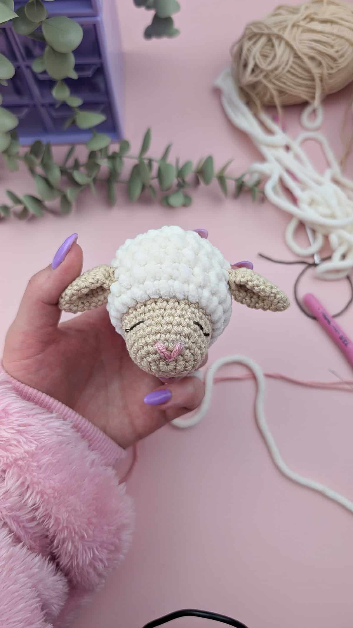lamb head with a embroidered face on a pink background