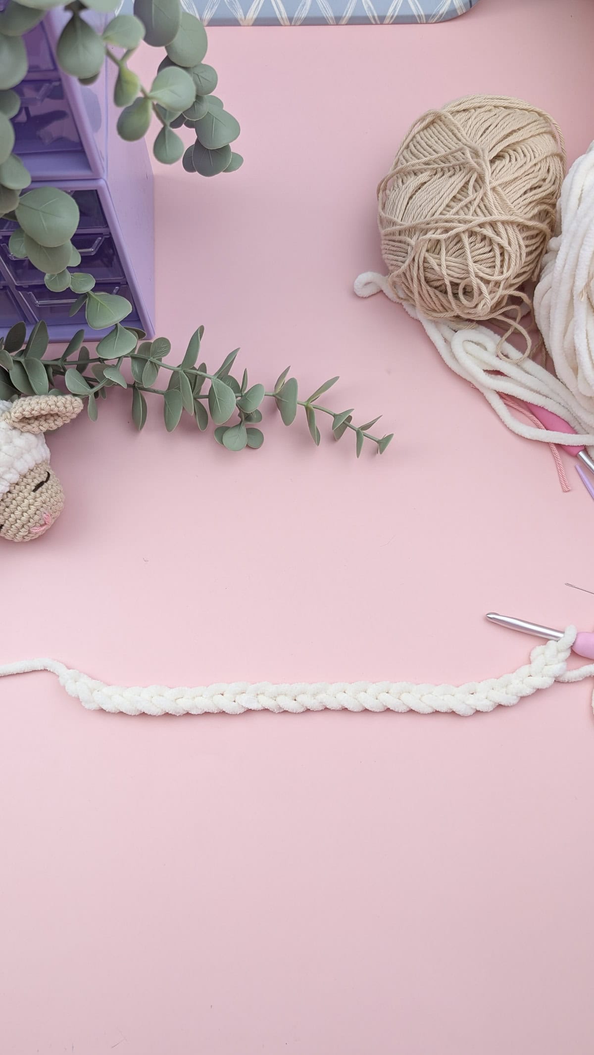 a white chenille yarn crochet chain on a pink background