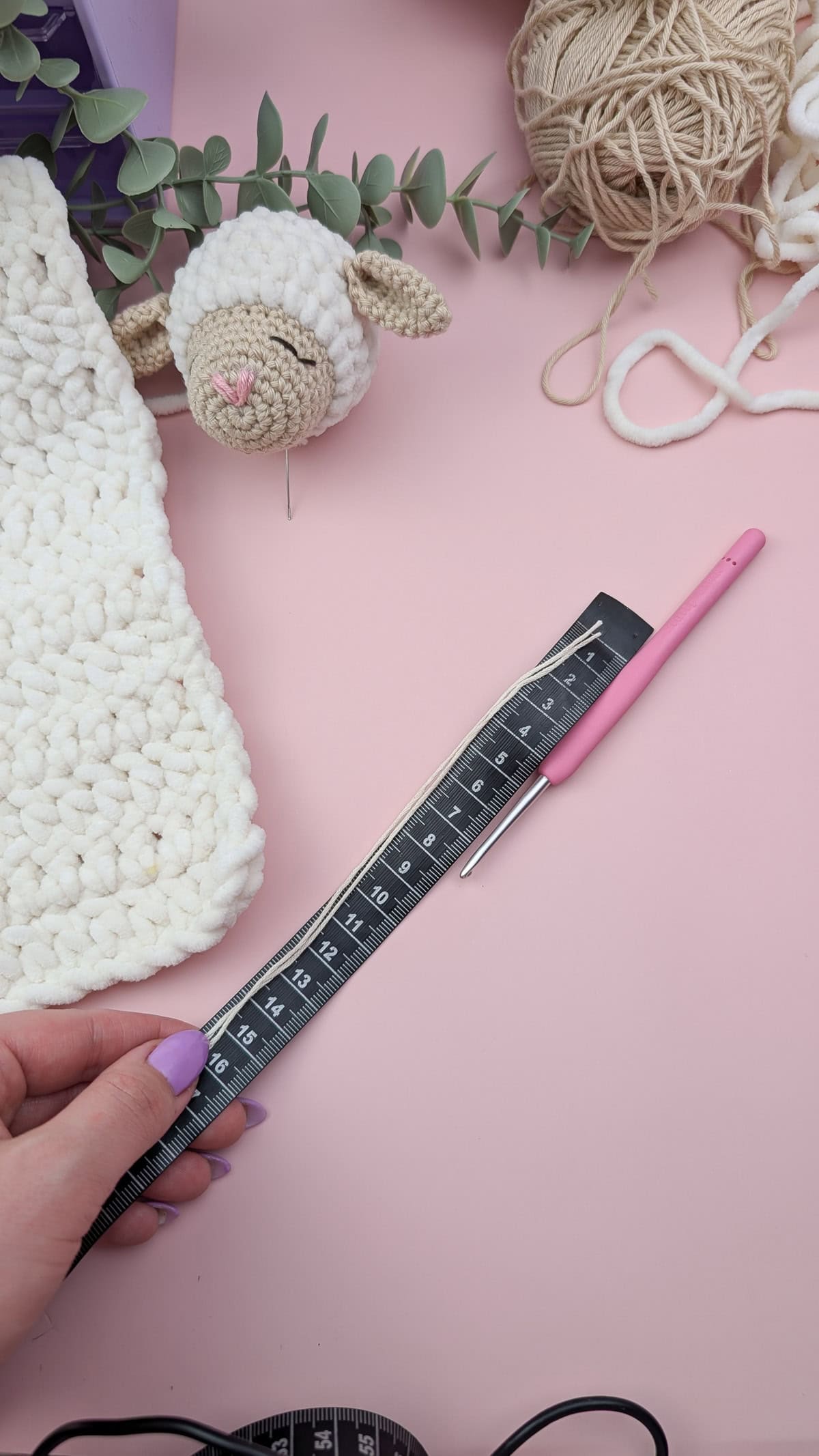 measuring tape, pink crochet hook and thread on a pink background