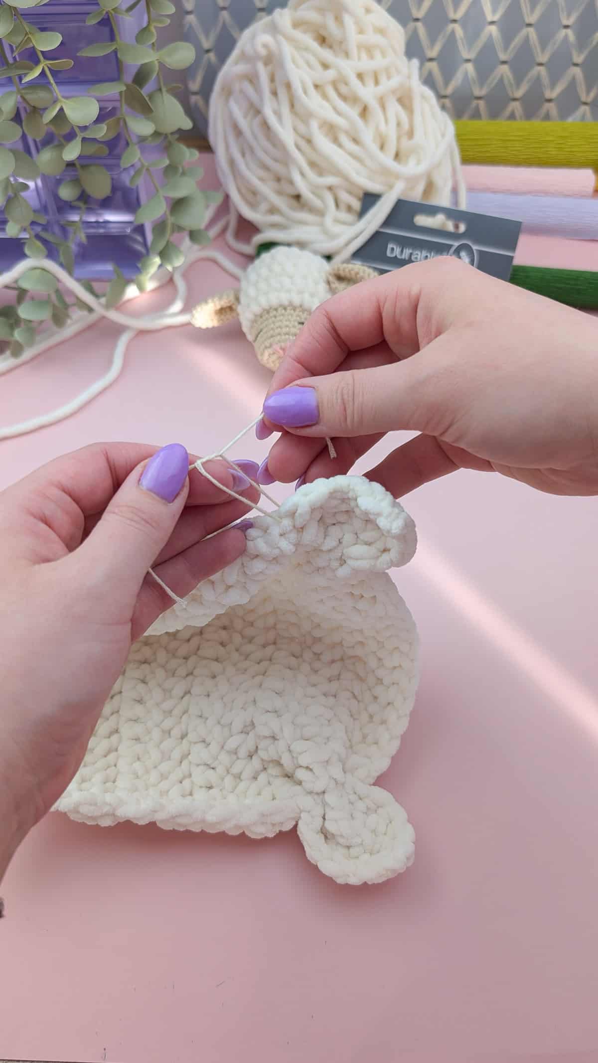 making the loveys feet in white chenille yarn on a pink background